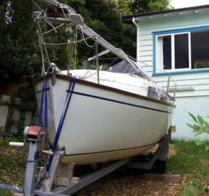 sailing boat on a trailer parked in front of house